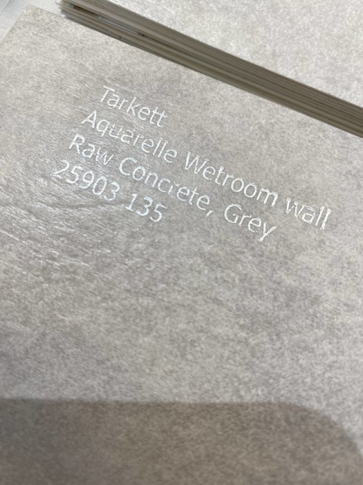 Textur av en grå Tarkett Aquarelle Wetroom wall matta med textdetaljer om produktserien.