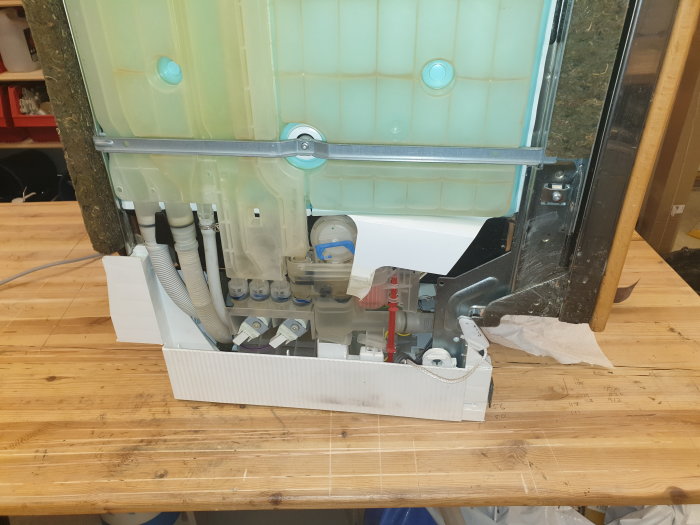 Maskineri på bänk med uppkopplade kablar och slangar, lossade skruvar och demonterade komponenter.