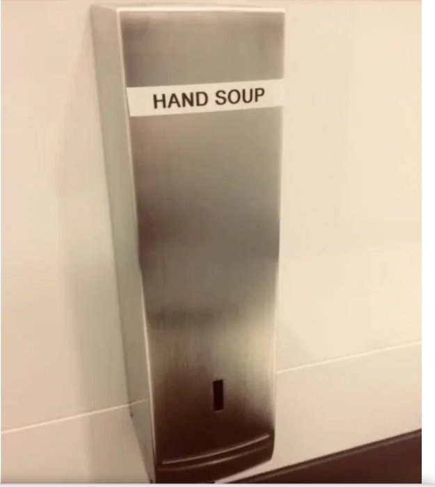 Tvåldispenser på en vägg med en felstavad etikett med texten "HAND SOUP" istället för "HAND SOAP".