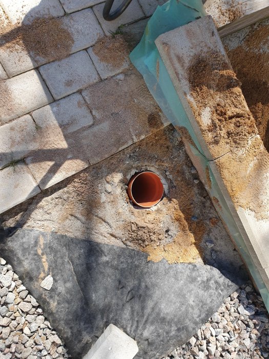 Ett borrat brunnshål med ett 160mm diameter foderör sticker upp från grunden, omgivet av sand och grus.