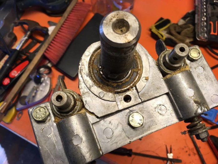 Delvis återmonterat lagerhus i gjuten aluminium med synlig spricka och rost, på en arbetsbänk med verktyg.