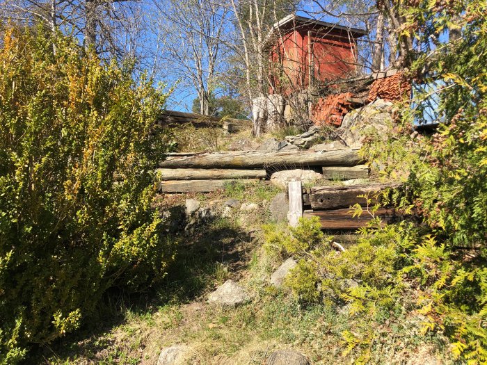 Gamla slitna slipers som används som stödmurar i en trädgård med vegetation.