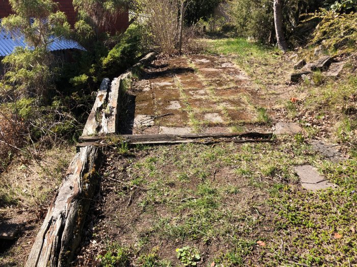 Gamla urlakade slipers använda som stödmur i en trädgård, omgivna av grönska.