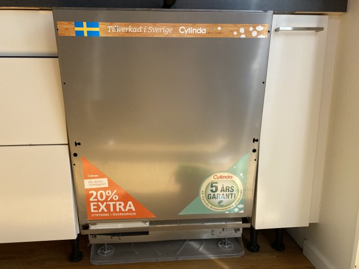 Diskmaskin med lossade skruvar på sidan och främre panelen delvis avtagen, klistermärken syns.