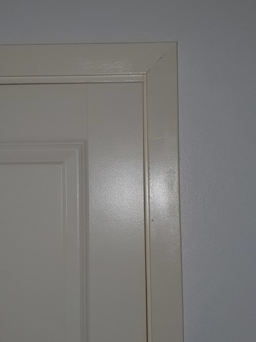 En närbild av en nymålad dörrkarm som visar en färgskillnad mot en vit vägg, vilket illustrerar valet av en annorlunda nyans.