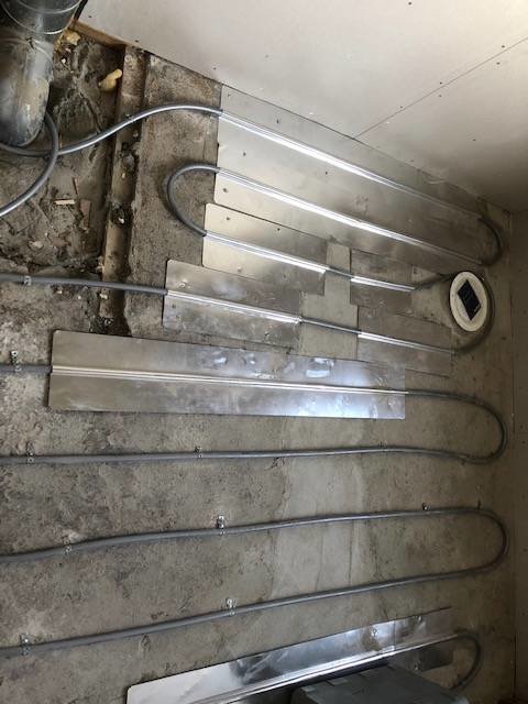 Handdukstork demonterad och placerad på golvet under pågående badrumsrenovering.