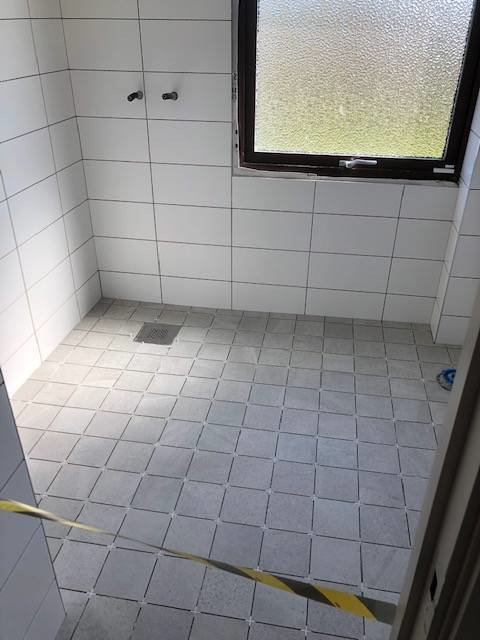 Renoverat badrum med kaklade väggar och golv samt centralt placerad golvbrunn.