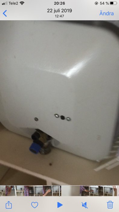 Varmvattenberedare med saknad svart avtappningsventil ovanför en blå ventil.