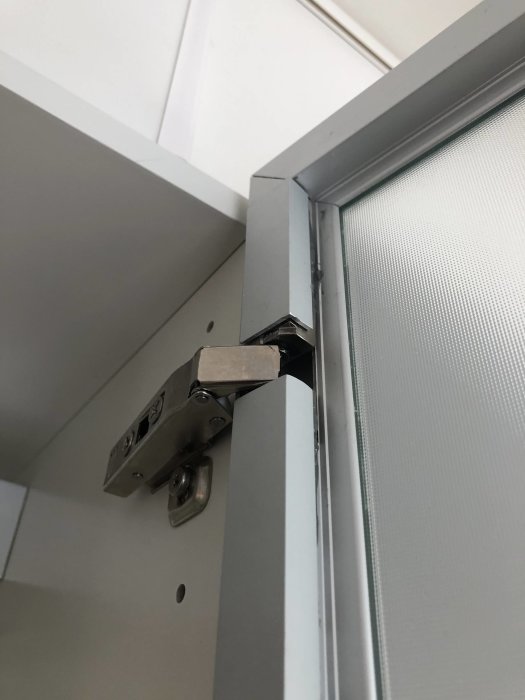 Aluminiumkantlister monterade på en skåpslucka med synliga gångjärn och epoxilim, som visar DIY-renoveringen.