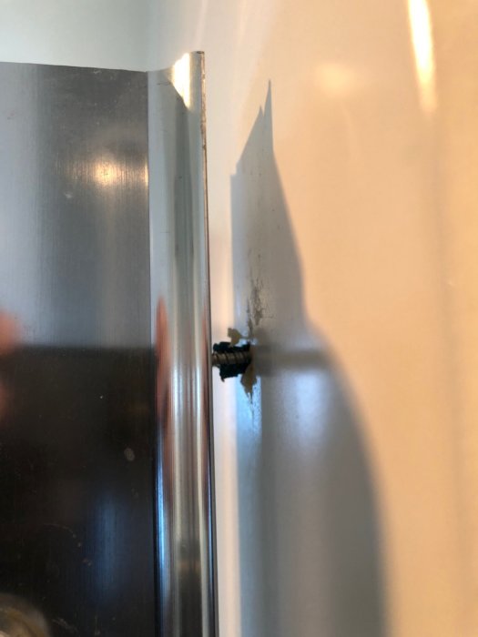 Duschväggens överkant där pluggen lossnat från gipset bakom kakelplattan.