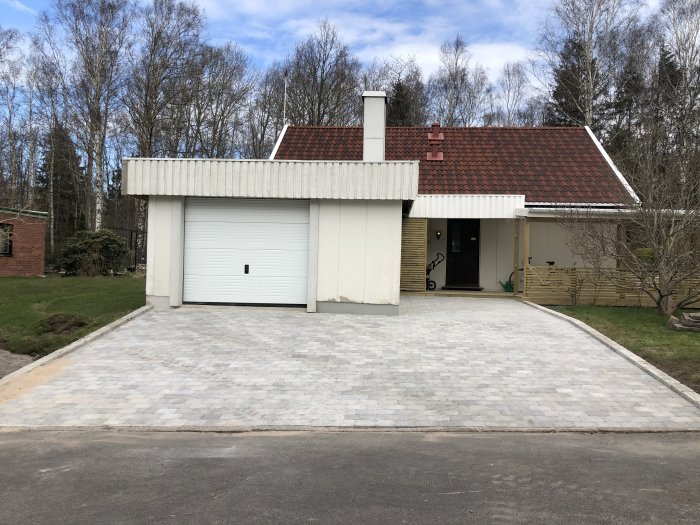 Hus från 1958 med tvåvåningsfasad i lättbetong och träpanel, tegeltak och vit garageport.