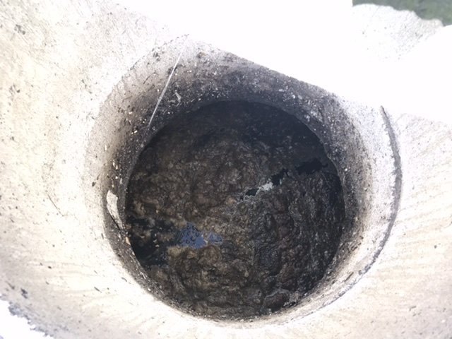 Överblick av en överfull avloppstank som visar tecken på blockering och behov av underhåll.