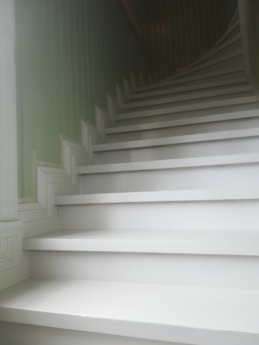 Nyrenoverad trappa målad i grå linoljefärg med vit sockel längs sidan.