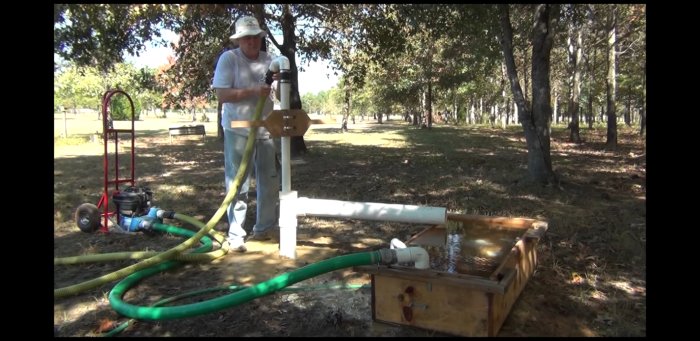 Person som använder en enkel borranordning för att borra brunn utomhus med pump och slangar.