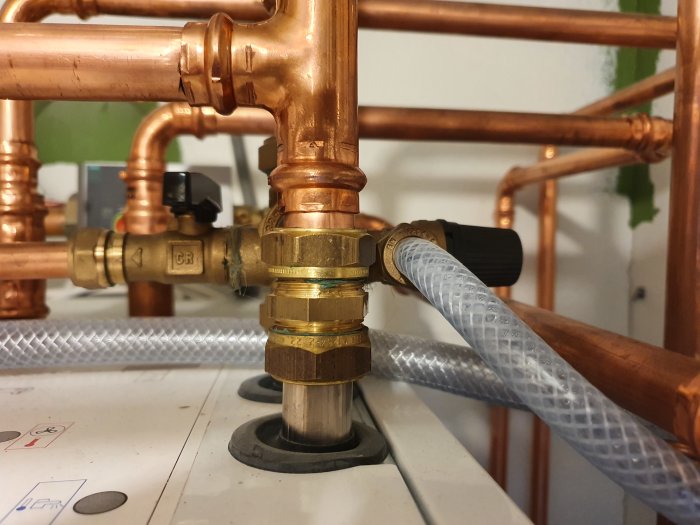 Detaljerad vy av kopparledningar och en mässingsventil, möjlig påfyllnadsventil för en värmepump.