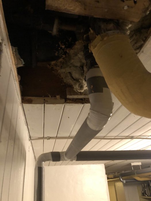 Synlig VVS-installation i ett källartak med grå Uponor PEX-rör och äldre kopparledningar intill träbjälkar.