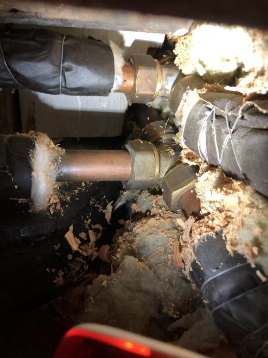 Bild av befintliga VVS-installationer i ett hus med kopparledningar och isolering i en krypgrund.