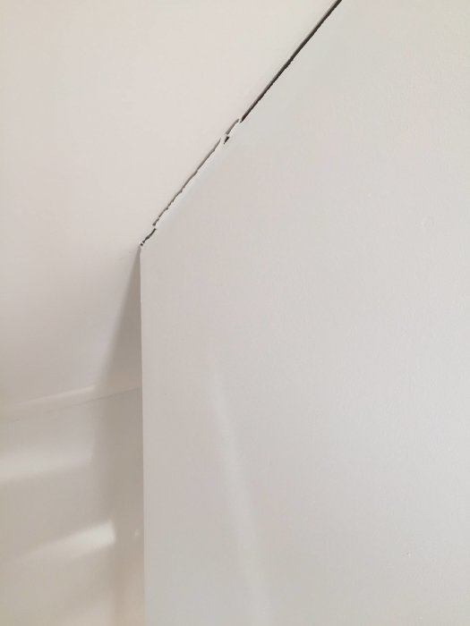 Sprække mellem væg og loft i et trappeområde, hvor malingen er revnet. Træhus, indflytning januar, bekymring for strukturel skade.