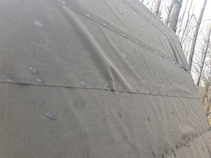 Nyinstallerad ytpapp på tak med asfaltsklister på spikhuvuden, klar för vidare renovering.