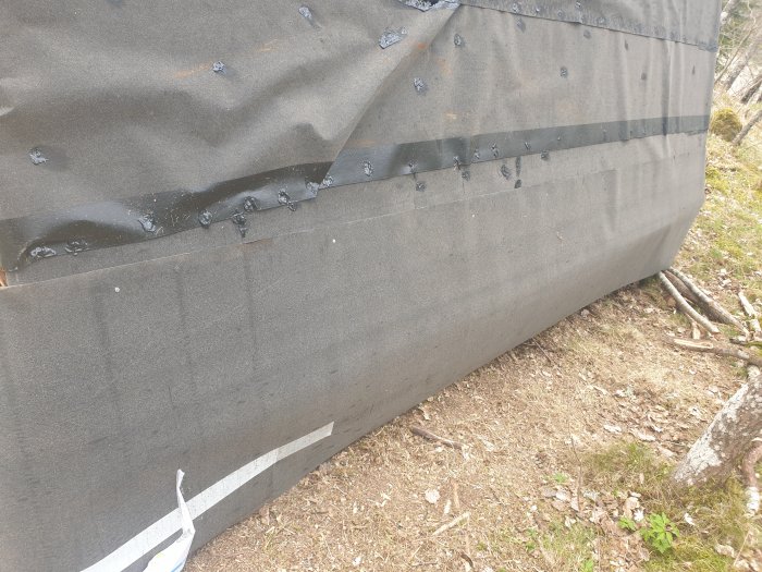 Nyinstallerat ytpappstak med synligt asfaltsklister på spikhuvuden och skarvar på en byggnad.