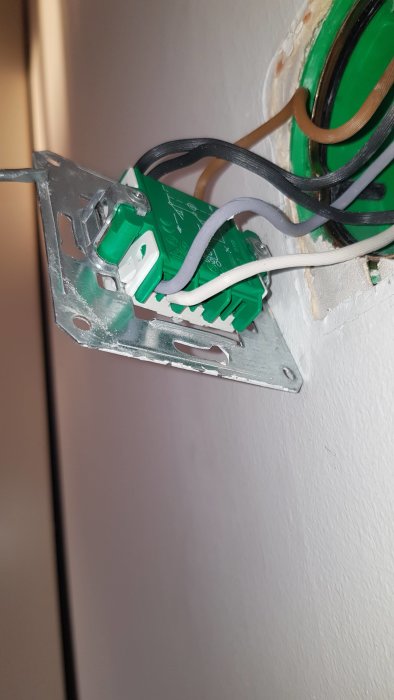 Öppen eldosa med installation av grön dimmerströmbrytare och exponerade elektriska kablar.