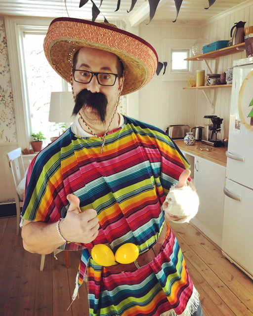 Person i färgglad poncho och sombrero håller upp tummen med bandage på pekfingret.