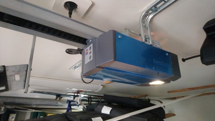 Garageportöppnare av märket Hörmann monterad i tak med synliga styrskenor och anvisningsknappar.