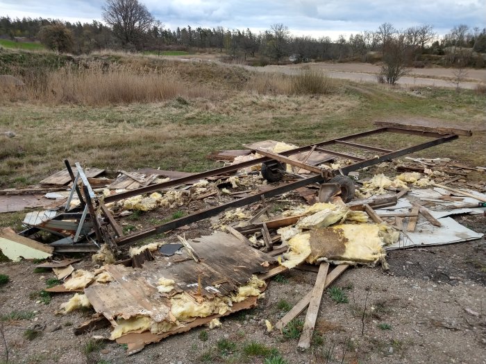 Nerrivet flak på en vagn med spik, isolering och virke utspritt på marken, omvandling till hus på hjul.