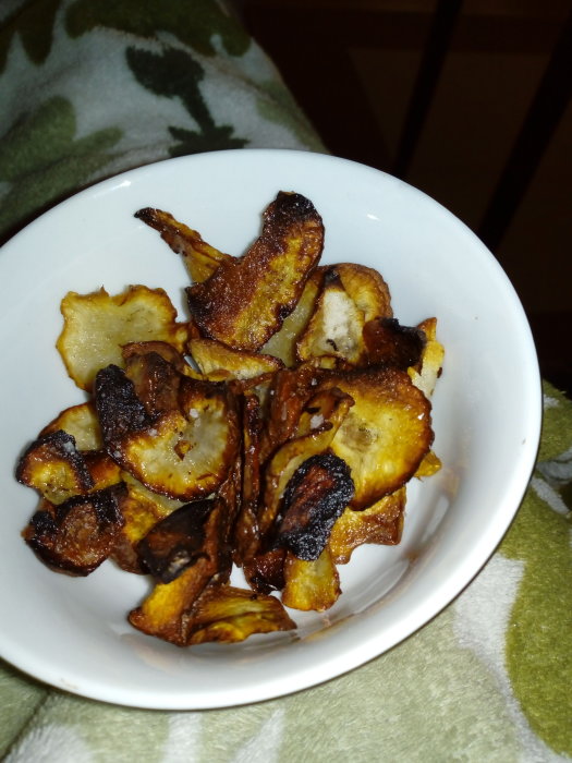 Hemgjorda jordärtskockschips i en vit skål, vissa delvis brunstekta.