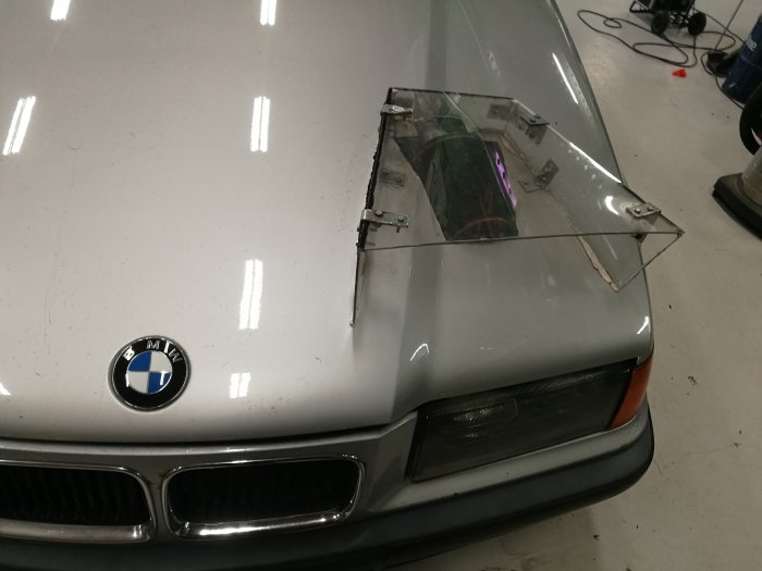 BMW-bil med en hemgjord genomskärning i motorhuven där ett sportluftfilter syns genom en plastlucka.