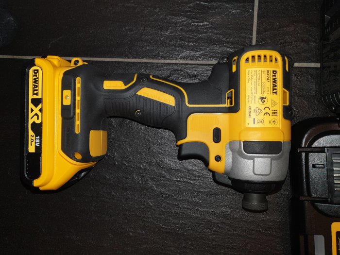 Oanvänd Dewalt 18v slagskruvdragare med batterier och laddare på ett mörkt underlag.