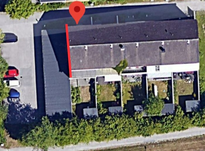 Flygbild av gavelradhus med rödmarkerad vägg mot garagelänga.