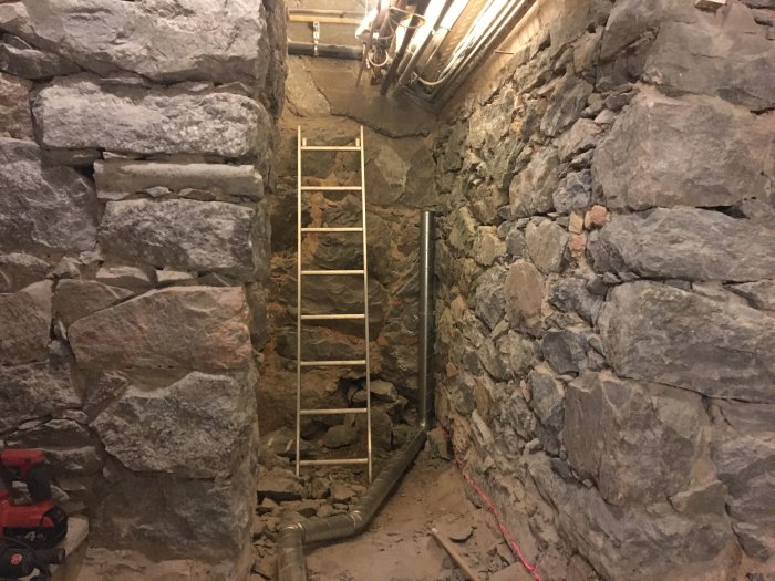 Renoveringsarbete med stenmurar, synliga rör och förberedelser för ventilation och värmesystem.
