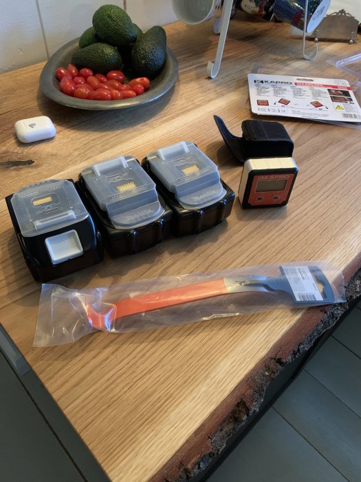 Nyinköpt orange vinkelhake och Makita-batterier på köksbänk med fruktskål i bakgrunden.