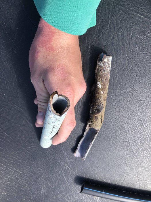 Skadat rör delat i två, hand visar in- och utsidan av rördelarna.