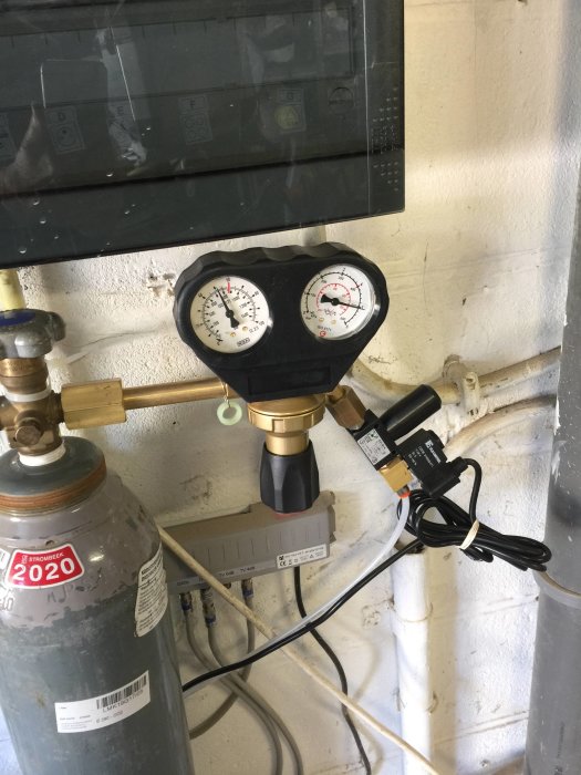 En CO2-anläggning med gasflaska, tryckmätare och regulatorer monterad på en vägg, använd för vattenbehandling.