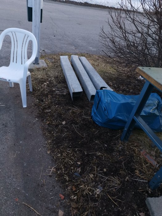 Betongplattor på marken nära plaststol och trädgårdsbord, rivningsavfall efter skorstensnedtagning.