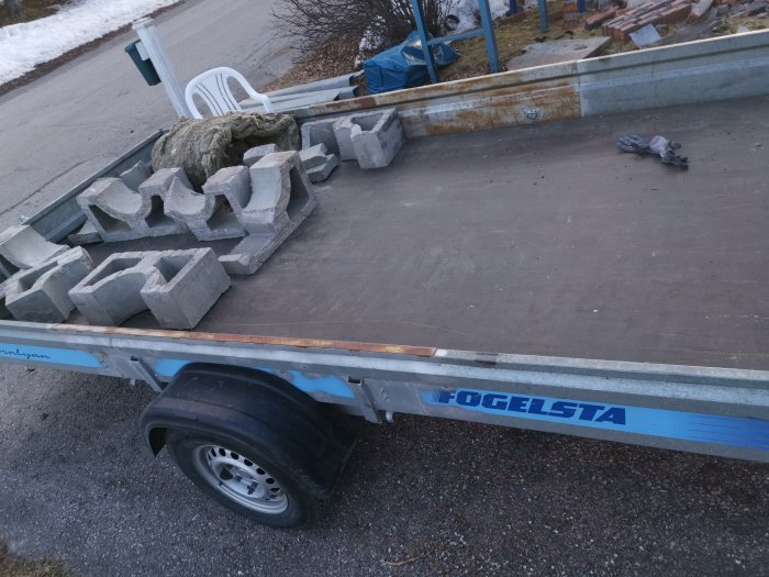 Delar av en demonterad skorsten och isoleringsmaterial på en släpvagn, indikerar rivningsavfall efter takarbete.