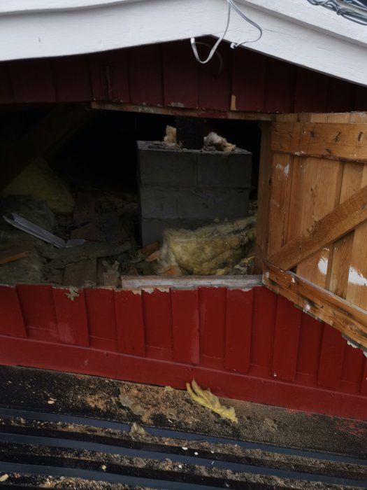 Delvis rivet tak med synliga isoleringsmaterial och rester av en avlägsnad skorsten.