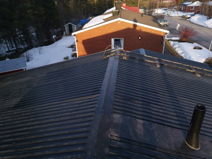 Väl utfört takarbete på en tegelvilla, med takstege och snöskydd i ett vintertidigt bostadsområde.