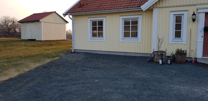 Fasaden på ett gult hus med röda detaljer innan tillbyggnad av amerikansk veranda.