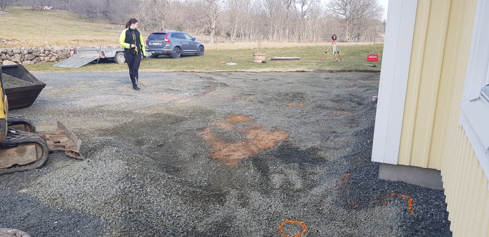 Byggplats för tillbyggnad av veranda med markerade mätningar och en person i arbetskläder.