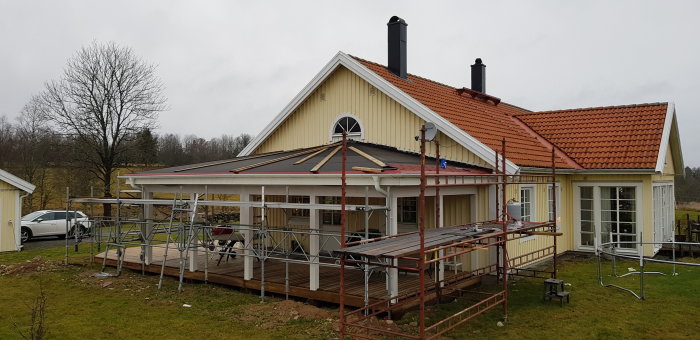 Hus under renovering med byggnadsställningar och nytt tak under konstruktion.