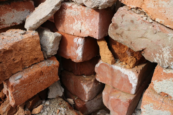 Hög med gamla röda och smutsiga tegelstenar staplade oorganiserat, synligt slitage och murbruk.