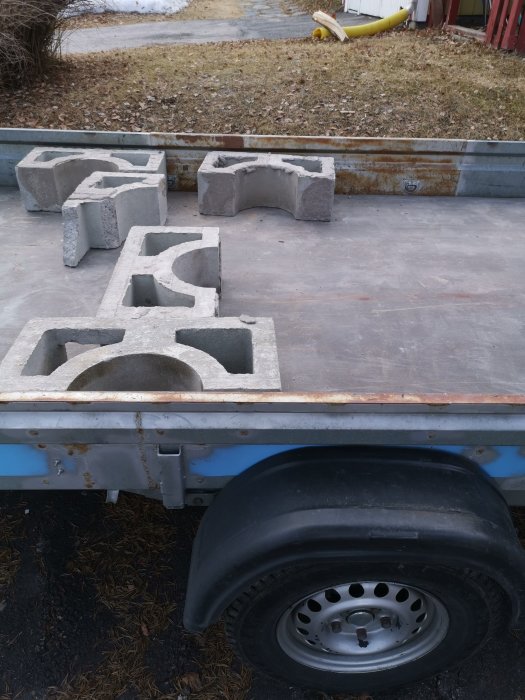 Dekorativa betongstenar lastade på släpvagn med synlig däckdel.