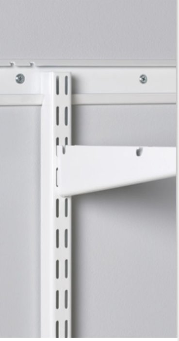 Stålskena fäst i vit vägg och tak med justerbar hyllarm.