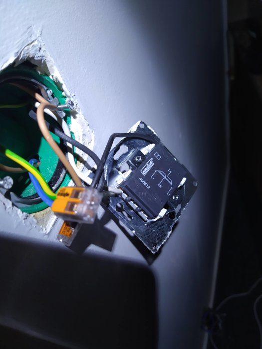 Eluttag med exponerade kablar och Wago-kopplingar öppet i vägg, indikerar möjlig felkoppling.