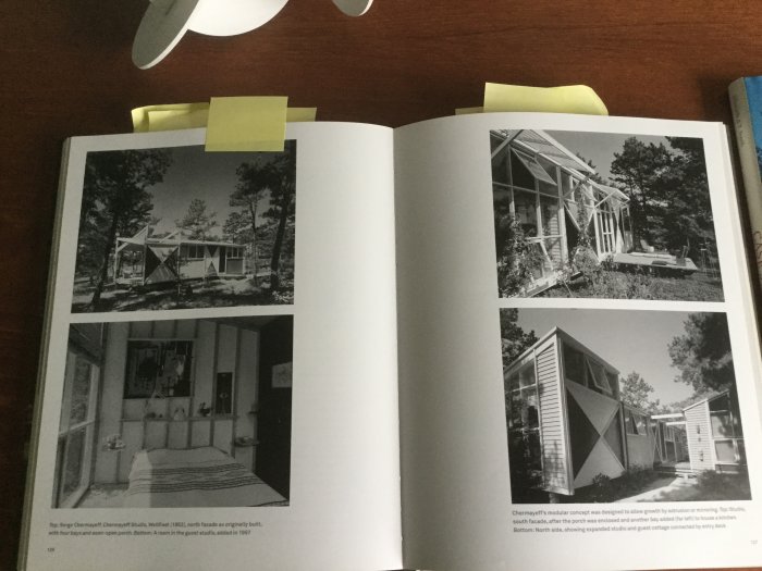 Öppen bok som visar svartvita fotografier av modernistiska hus och interiörer i en bok om Cape Cod-arkitektur.