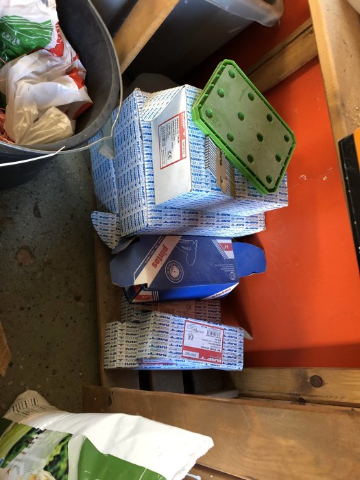 Öppnad låda med Paslode märkesvaror och spikförpackningar på en röd arbetsbänk i en verkstad.