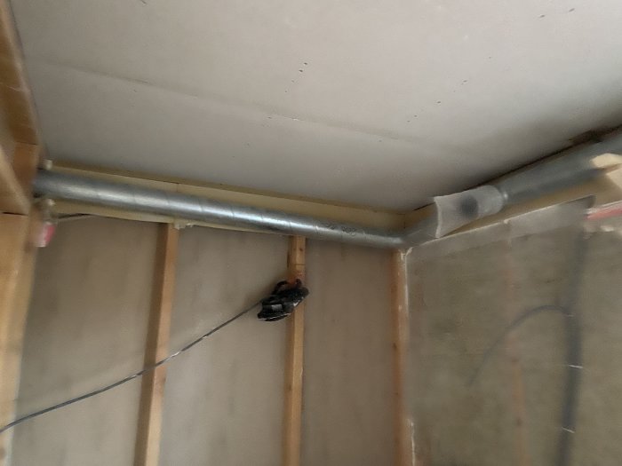 Bild av ett under-renovering badrumstak med en exponerad spirorörskanal och isolering.
